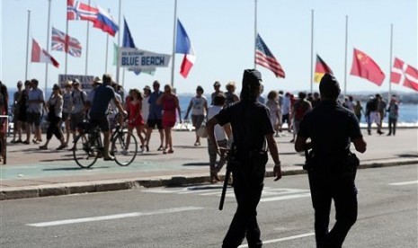 Polisi berpatroli dekat lokasi serangan truk di Promenade des Anglais, Nice, Prancis, Sabtu, 16 Juli 2016. Tampak bendera dikibarkan setengah tiang.