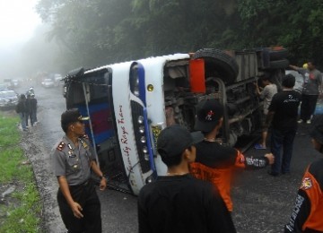 Polisi bersama warga berusaha mengevakuasi bus yang terbalik. (ilustrasi)