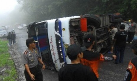 Polisi bersama warga berusaha mengevakuasi bus yang terbalik. (ilustrasi)