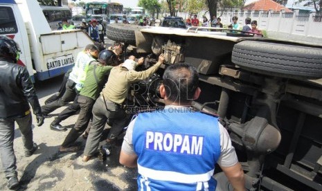 Polisi bersama warga mengevakuasi mobil minibus yang terbalik. (ilustrasi)