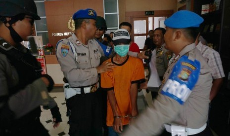 Polisi bersenjata lengkap menjaga pelaku penabrak pengemudi ojek online berinisial SBH (41) saat ungkap kasus di Polres Metro Tangerang, Banten, Jumat (10/3).