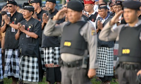 Polisi dan anggota satuan pengamanan adat atau Pecalang memberi penghormatan saat apel kesiagaan pasukan Operasi Lilin 2015 di Lapangan Puputan Margarana, Denpasar, Rabu (23/12).