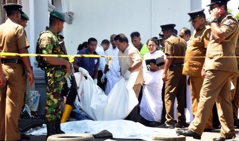 Polisi dan pekerja penyelamat memeriksa sisa-sisa korban di tempat kejadian setelah ledakan di Gereja St Anthony di Kochchikade di Kolombo, Sri Lanka, Ahad (21/4/2019). 