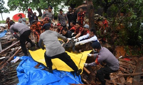 Polisi dan relawan mengevakuasi korban tewas akibat Tsunami yang tertimbun di bawah reruntuhan di kawasan Carita, Banten, Jawa Barat, Senin (24/12/2018)