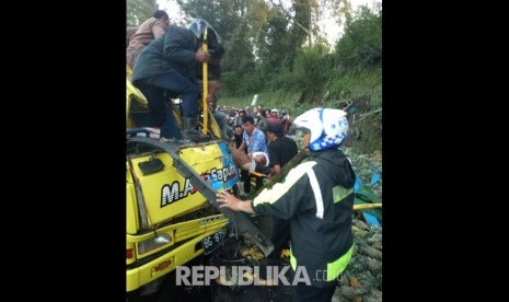 Polisi dibantu warga mengevakuasi korban kecelakaan di Jl Raya Puncak