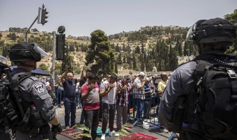 Polisi Israel berjaga-jaga saat warga Palestina melaksanakan shalat Jumat di luar Gerbang Lion di Kota Tua Yerusalem, Jumat (21/7).