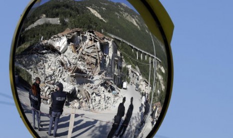 Polisi Italia tampak dari cermin lalu lintas dekat rumah yang hancur akibat gempa bumi di Pescara Del Tronto, Italia, Kamis, 25 Agustus 2016.