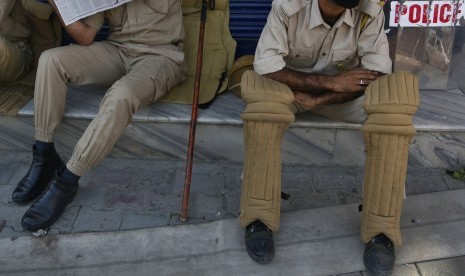 Polisi Kashmir duduk-duduk di depan sebuah toko yang tutup di Srinagar, Kashmir yang dikuasai India, Kamis (22/8).