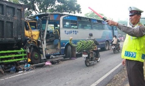 Polisi lalu lintas mengatur jalan di sebelah bus yang terguling.