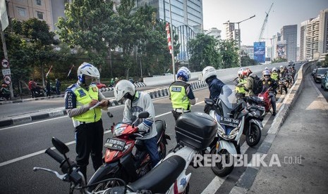 Polisi Lalu Lintas menilang pengendara sepeda motor yang melintas di Jalan Layang Non Tol Kampung Melayu-Tanah Abang, Karet Tengsin, Jakarta, Senin (12/8). Pelanggaran lalu lintas terus terjadi karena rendahnya sikap tertib berlalu lintas dari pengguna jalan.