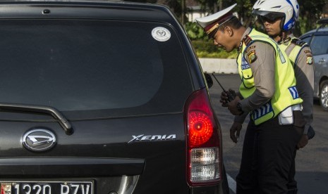 Polisi Lalu Lintas Polda Metro Jaya memberikan imbauan kepada pengendara yang kendaraannya berpelat nomor genap saat uji coba penerapan sistem lalu lintas plat Ganjil Genap di Jalan Medan Merdeka Barat, Jakarta, Rabu (27/7). 