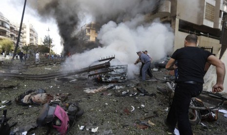  Polisi Lebanon berusaha memadamkan mobil yang terbakar,  akibat ledakan bom dekat Kedutaan Besar Iran  di Beirut, Lebanon, Selasa (19/11).   (AP/Hussein Malla) 