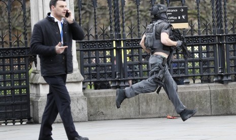 Polisi London bersenjata lengkap berlari di area kompleks Gedung Parlemen  saat insiden penyerangan berlangsung di Jembatan Westminster, London.