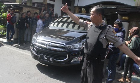 Polisi melakukan pengamanan saat mobil yang ditumpangi para petugas Komisi Pemberantasan Korupsi (KPK) melintas usai melakukan penggeledahan di Kota Malang.