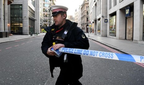 Polisi memasang garis batas polisi di jalan dekat lokasi penusukan di London Bridge, Jumat (29/11).