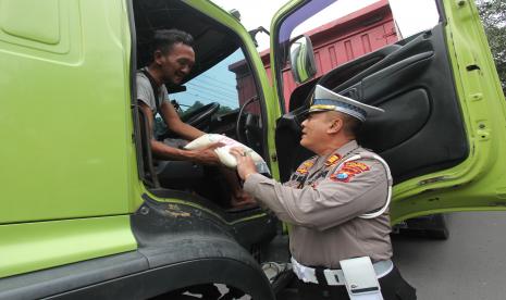 Polisi membagikan beras kepada sopir trailer di Jalan Jakarta, Surabaya, Jawa Timur, Jumat (9/9/2022). Pembagian bantuan bahan pangan di sejumlah lokasi di wilayah hukum Polres Pelabuhan Tanjung Perak Surabaya itu untuk meringankan beban ekonomi masyarakat yang terdampak kenaikan harga bahan bakar minyak (BBM).