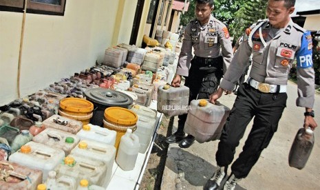 Polisi membawa miras tradisional yang disita dari operasi selama sepekan di Polres Muna, Kabupaten Muna, Sulawesi Tenggara, Selasa (1/5).