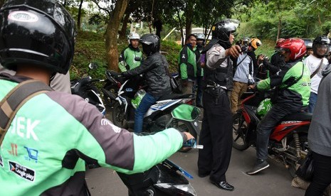 Polisi membubarkan kerumunan pengemudi ojek online untuk mengantisipasi terjadinya gesekan dengan pengemudi angkutan kota (angkot) di Jembatan Panus, Depok, Jawa Barat, Selasa (21/3). 