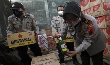 Polisi memeriksa isi kardus minuman keras (miras) untuk kemudian disita, usai melakukan penggerebekan di gudang penyimpanan miras.