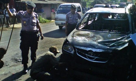 Polisi memeriksa mobil milik anggota Front Pembela Islam (FPI) yang dibakar massa setelah terjadinya bentrok antara FPI dengan warga di Kecamatan Sukorejo, Kendal, Jawa Tengah, Kamis (18/7)