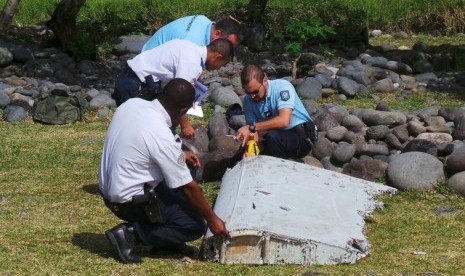  Polisi memeriksa potongan pesawat yang ditemukan di Pantai Saint-Andre, di kepulauan La Reunion di Laut Hindia, (30/7).