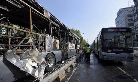 Polisi memeriksa sisa bus Transjakarta yang terbakar di Halte Universitas Indonesia (UI) Salemba, Jakarta, Jumat (3/7). 