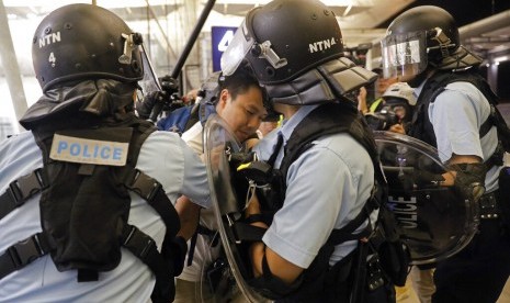 Polisi menahan seorang demonstran di Bandara Internasional Hong Kong, Selasa (13/8).