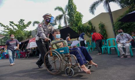 Polisi mendorong kursi roda penyandang disabilitas usai mengikuti vaksinasi COVID-19 di Mapolres Pekalongan Kota, Jawa Tengah, Sabtu (21/8/2021). Polres Pekalongan Kota dan pemerintah setempat mengadakan vaksin COVID-19 untuk warga disabilitas dan ibu hamil dengan target pencapaian sebanyak 100 orang penyandang disabilitas dan 250 orang ibu hamil.