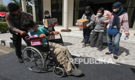 Polisi mendorong kursi roda penyandang disabilitas yang telah divaksin Covid-19  (ilustrasi)