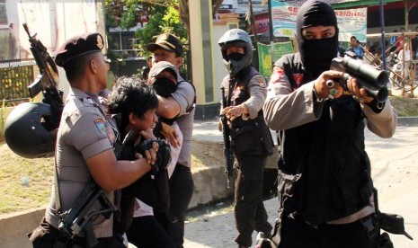   Polisi mengamankan dua mahasiswa saat terjadi bentrokan antara polisi dan mahasiswa di depan Kampus Universitas Muhammadiyah (Unismuh) Makassar, Sulsel, Senin (15/9). (Antara/Yusran Uccang)