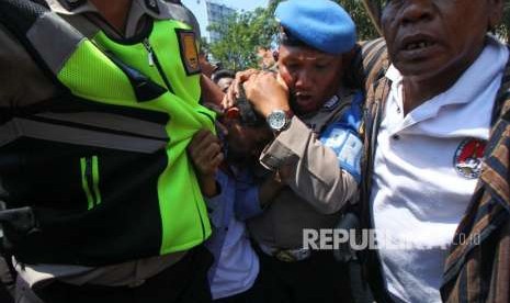 Polisi mengamankan seorang pemuda dari amukan massa saat aksi yang melibatkan dua kubu yang mendeklarasikan #2019 Ganti Presiden dan kubu yang menentang dan menyerukan cinta NKRI, di Jalan Indrapura, Surabaya, Jawa Timur, Ahad (26/8).