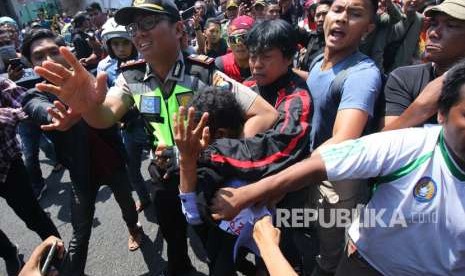 Polisi mengamankan seorang pemuda dari amukan massa saat aksi yang melibatkan dua kubu yang mendeklarasikan #2019 Ganti Presiden dan kubu yang menentang dan menyerukan cinta NKRI, di Jalan Indrapura, Surabaya, Jawa Timur, Ahad (26/8).