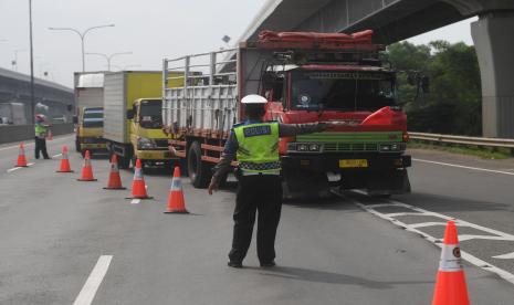 Polisi mengarahkan angkutan barang untuk keluar dari Tol Jakarta-Cikampek melalui pintu tol Karawang Barat di Karawang, Jawa Barat, Rabu (23/12/2020).