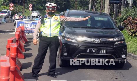 Polisi mengarahkan pengendara di jalur wisata Puncak, Gadog, Kabupaten Bogor, Jawa Barat.  Jalur Puncak-Cianjur, Jawa Barat, ramai lancar meski di sejumlah titik rawan kemacetan terlihat laju kendaraan tersendat, namun tidak sampai menyebabkan macet panjang, sebagai upaya mengantisipasi macet, petugas sempat memberlakukan sistem satu arah menuju Bogor menjelang petang.