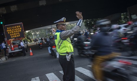 Polisi mengatur arus lalu lintas pada hari pertama uji coba perluasan kawasan ganjil genap di persimpangan Pancoran, Jakarta, Senin (2/7).