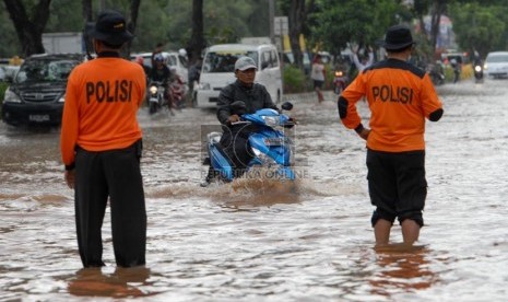   Polisi mengatur lalu lintas di ruas jalan yang terendam banjir di Jalan Boulevard Barat, Kelapa Gading, Jakarta Utara, Jumat (17/1). (Republika/Rakhmawaty La'lang)