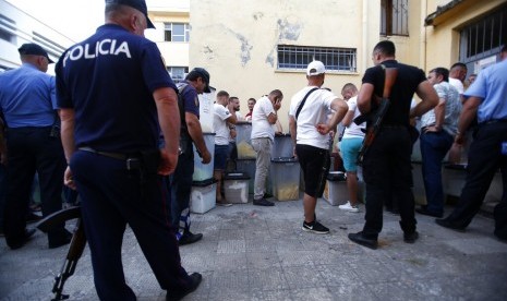 Polisi mengawal panitia pemilihan daerah yang antre mengantar surat suara di pusat penghitungan suara di Shkoder, Albania Utara, Ahad (30/6).