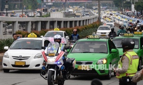 Polisi mengawal ribuan taksi saat meninggalkan aksi di depan DPR, Jakarta, Selasa (22/3).