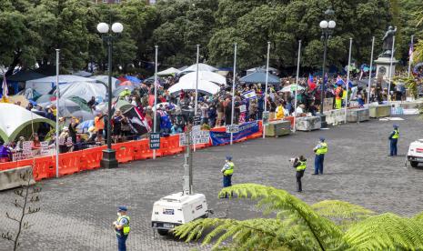 Polisi mengawasi warga yang mengikuti aksi protes terhadap mandat vaksin di Wellington, Selandia Baru, Senin (14/2/2022). 