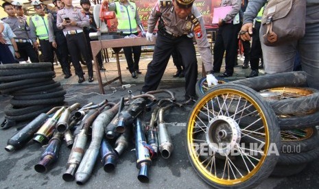 Polisi mengecek knalpot yang tidak memenuhi standard saat rilis hasil operasi balap liar, di Polresta, Banyuwangi, Jawa Timur, Rabu (22/1/2020).