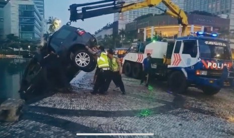 Polisi mengevakuasi mobil Land rover Freelander yang tercebur ke kolam Bundaran HI, Jakarta.