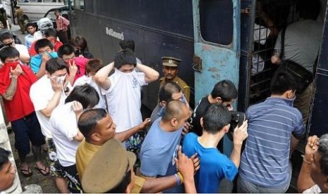 Polisi menggelandan ratusan warga Cina tersangka penipuan keuangan di Internet ke truk tahanan.