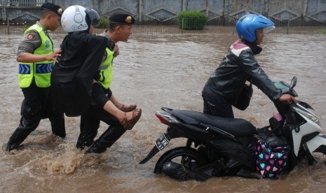 Polisi menggendong seorang ibu berusaha melintasi banjir di depan Pabrik Kahatex kawasan Rancaekek, Kabupaten Bandung, Jawa Barat, Selasa (1/11).