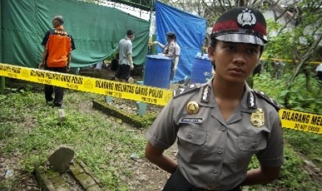 Polisi menjaga area makam saat otopsi mayat.