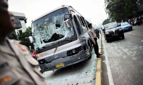 Polisi menjaga Bus Transjakarta yang dirusak massa di Jl Mampang Prapatan, Jakarta Selatan, Jumat (13/7).  (Yogi Ardhi/Republika)