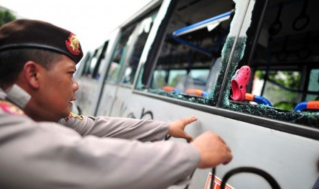 Polisi menjaga Bus Transjakarta yang dirusak massa di Jl Mampang Prapatan, Jakarta Selatan, Jumat (13/7).  (Yogi Ardhi/Republika)