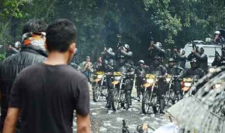 Polisi menodongkan gas air mata kepada demonstran.