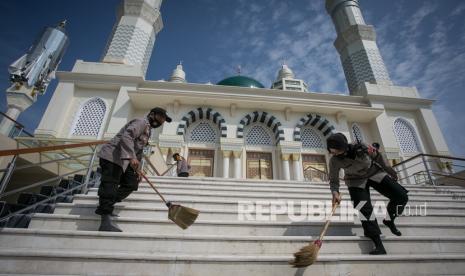 Polisi menyapu halaman Masjid Agung saat kegiatan bersih-bersih masjid jelang Ramadhan di Karanganyar, Jawa Tengah, Jumat (1/4/2022). Kegiatan membersihkan masjid yang mulai dibuka untuk umum setelah selesai direvitaliasi tersebut untuk memberikan rasa nyaman kepada umat Islam menjalankan ibadah di bulan Ramadhan. 