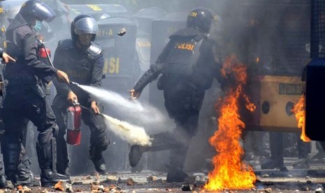  Polisi merusaha memadamkan api dari sebuah bom molotov yang dilemparkan warga saat terjadi bentrokan antara warga dan polisi di Kelurahan Mario Makassar, Sulsel, Senin (21/10).      (Antara/Yusran Uccang)