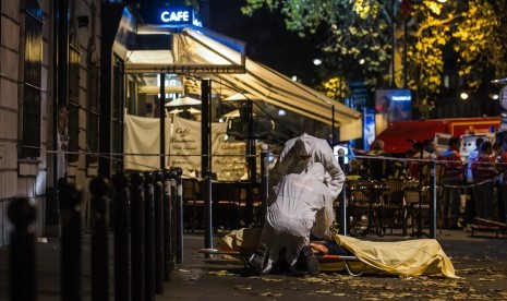 Polisi sedang memeriksa tubuh korban tewas serangan penembakan di luar gedung konser Bataclan di Paris, Prancis, Jumat (13/11).